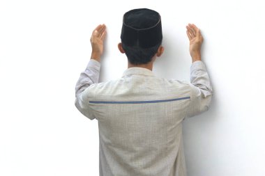 Asyalı Müslüman bir adam ellerini kaldırıp kameraya dönük dua eder..