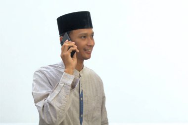 Asyalı Müslüman bir adam mutlu bir ifadeyle akıllı telefon kullanıyor..