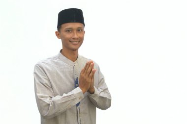 Beyaz gömlekli Asyalı Müslüman adam beyaz arka planda izole edilmiş kameraya gülümsüyor.