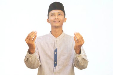 Asyalı Müslüman bir adam iki elini kaldırarak dua ediyor.