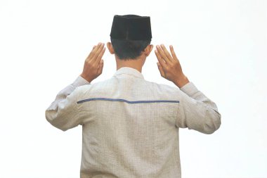 Asyalı Müslüman bir adam iki elini de kameraya kaldırır.