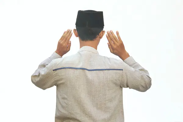 Asyalı Müslüman bir adam iki elini de kameraya kaldırır.