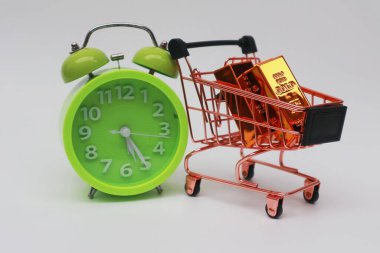 Tramvayda altın külçeleri beyaz bir arka planda çalar saatin yanında.