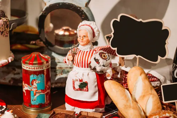 Noel süslerinde şenlikli ekmekler, porselen bir büyükanne figürü ve kişisel mesajlar için yazılabilir bir tabela yer alıyor.