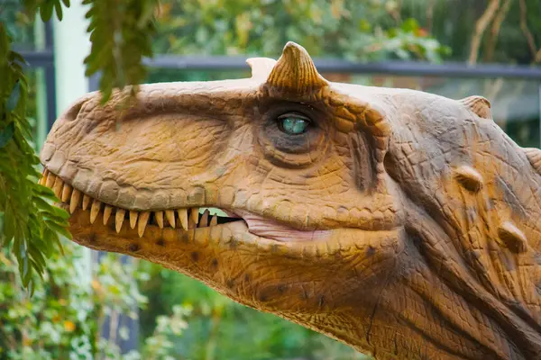 Bir Carnotaurus düşük bitki örtüsünün arasında durur, kaslı yapısı vahşi araziyle harmanlanmış, gözleri çevreyi yırtıcı bir odak ile tarıyor..