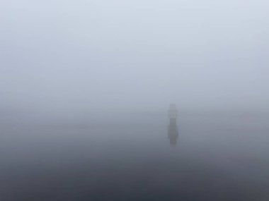 Yoğun bir sabah sisinde ıssız deniz feneri.