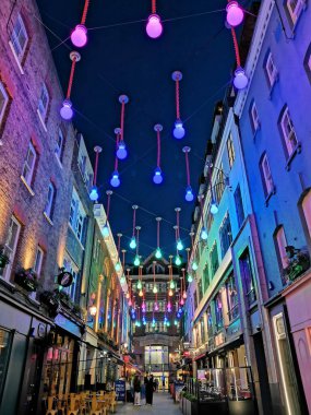 Akşam sokağında ışıklar ve neon ışıklarla süslenmiş. Carnaby, Soho 'da bir ara sokakta. Dekoratif ışıklarla aydınlatılmış.