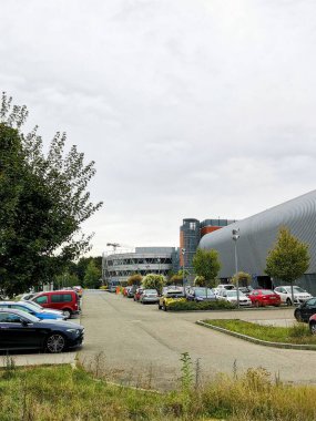CEITEC Masaryk Üniversitesi ve Çek Cumhuriyeti 'nin Brno kentindeki Spor Araştırmaları Fakültesi manzarası. Daha uzak bir manzara. Modern mimari. Bulutlu ve gri. Ağaç ve arabalar. Yol ve çimenler. 