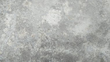 Beton duvarlar, çatlaklar ve deliklerle gri ve beyazdır. Duvarlar eski ve yıpranmış.