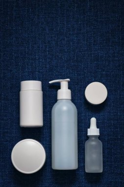 Lacivert (kot) arka planda beyaz ambalajlı kozmetik ürünlerinin bileşimi