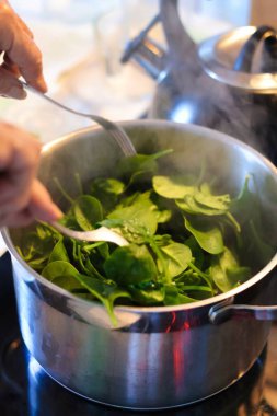 Bebek ıspanağın tencerede hazırlanmasına yakın durun.