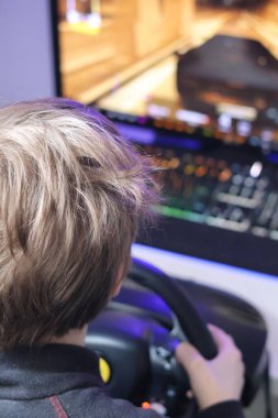 Direksiyon simidi kullanarak bilgisayarda yarış yapan bir çocuk.