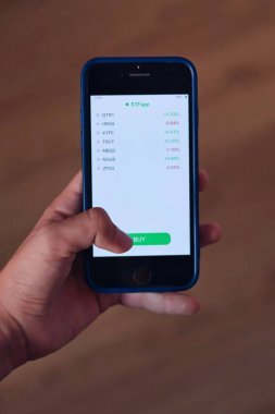 Birden fazla ETF tırnak içinde taşınabilir yatırım kavramına sahip akıllı telefon görüntüleme portföyü tutan eller