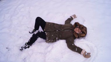 Kız karda yatıyor ve kar meleği yapıyor. Yüksek kalite fotoğraf