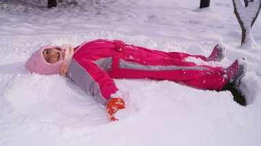 Kız karda yatıyor ve kar meleği yapıyor. Yüksek kalite fotoğraf