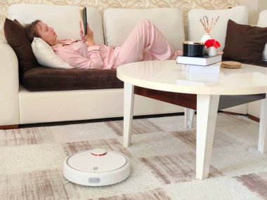 Robot elektrik süpürgesi çalışırken kadın dinleniyor. Yüksek kalite fotoğraf