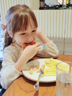 Küçük kız restoranda pizza yiyor. Yüksek kalite fotoğraf