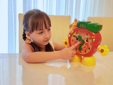 Küçük kız saati teker teker öğreniyor. Yüksek kalite fotoğraf