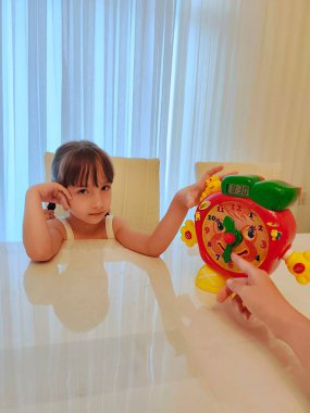 Küçük kız saati teker teker öğreniyor. Yüksek kalite fotoğraf