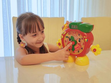 Küçük kız saati teker teker öğreniyor. Yüksek kalite fotoğraf