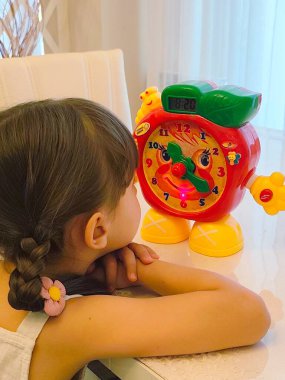 Küçük kız saati teker teker öğreniyor. Yüksek kalite fotoğraf