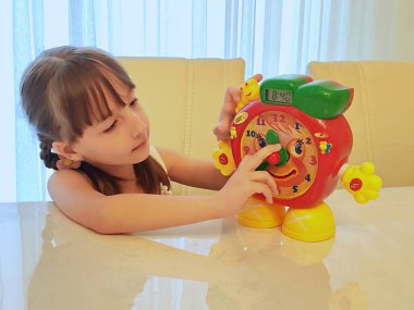 Küçük kız saati teker teker öğreniyor. Yüksek kalite fotoğraf