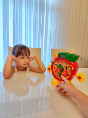 Küçük kız saati teker teker öğreniyor. Yüksek kalite fotoğraf