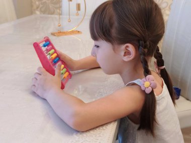 Yeni yürümeye başlayan kız tezgah kullanıyor. Evde eğitim görüyor. Yüksek kalite fotoğraf