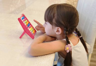 Yeni yürümeye başlayan kız tezgah kullanıyor. Evde eğitim görüyor. Yüksek kalite fotoğraf