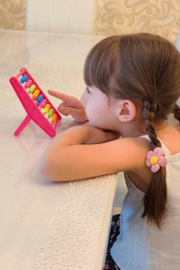 Yeni yürümeye başlayan kız tezgah kullanıyor. Evde eğitim görüyor. Yüksek kalite fotoğraf