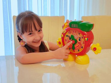 Küçük kız saati teker teker öğreniyor. Yüksek kalite fotoğraf