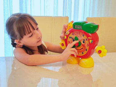 Küçük kız saati teker teker öğreniyor. Yüksek kalite fotoğraf