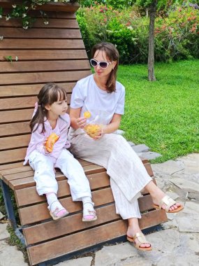 Anne ve kızı yaz günü parkta yemek yiyorlar. Yüksek kalite fotoğraf