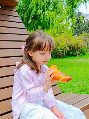 Küçük kız, parktaki çikolatalı çörekleri yiyor. 