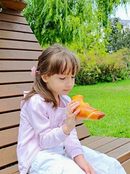Küçük kız, parktaki çikolatalı çörekleri yiyor. 