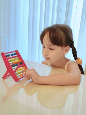 Yeni yürümeye başlayan kız tezgah kullanıyor. Evde eğitim görüyor. Yüksek kalite fotoğraf