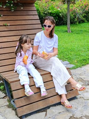 Anne ve kızı yaz günü parkta yemek yiyorlar. Yüksek kalite fotoğraf