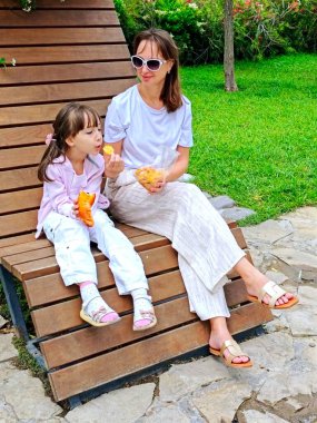 Anne ve kızı yaz günü parkta yemek yiyorlar. Yüksek kalite fotoğraf