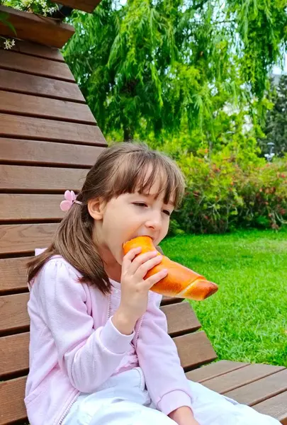 Küçük kız, parktaki çikolatalı çörekleri yiyor. 