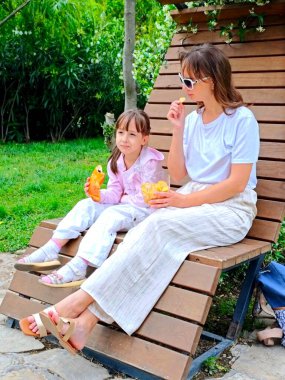 Anne ve kızı yaz günü parkta yemek yiyorlar. Yüksek kalite fotoğraf