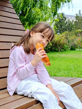 Küçük kız, parktaki çikolatalı çörekleri yiyor. 