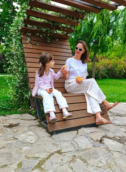 Anne ve kızı yaz günü parkta yemek yiyorlar. Yüksek kalite fotoğraf