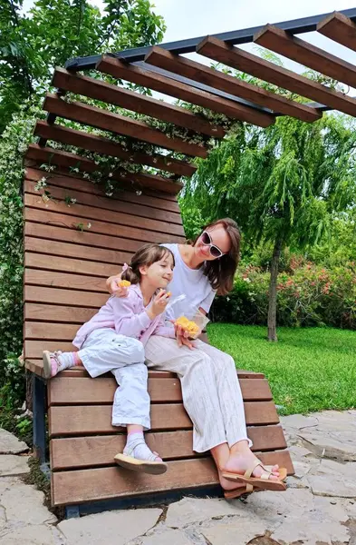 Anne ve kızı yaz günü parkta yemek yiyorlar. Yüksek kalite fotoğraf