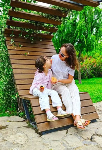 Anne ve kızı yaz günü parkta yemek yiyorlar. Yüksek kalite fotoğraf