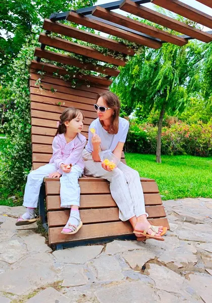 Anne ve kızı yaz günü parkta yemek yiyorlar. Yüksek kalite fotoğraf