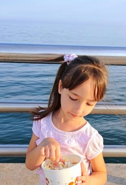 Küçük kız deniz kenarındaki parkta patlamış mısır yiyor. Yüksek kalite fotoğraf