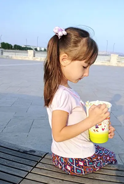 Küçük kız deniz kenarındaki parkta patlamış mısır yiyor. Yüksek kalite fotoğraf