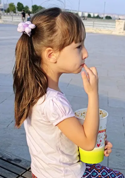 Küçük kız deniz kenarındaki parkta patlamış mısır yiyor. Yüksek kalite fotoğraf