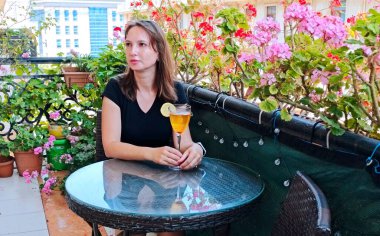 Kokkuyruklu kadın çiçek açan balkonda oturuyor. Yüksek kalite fotoğraf