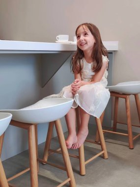 Kız mutfak masasında oturuyor ve kahvaltıyı bekliyor. Yüksek kalite fotoğraf